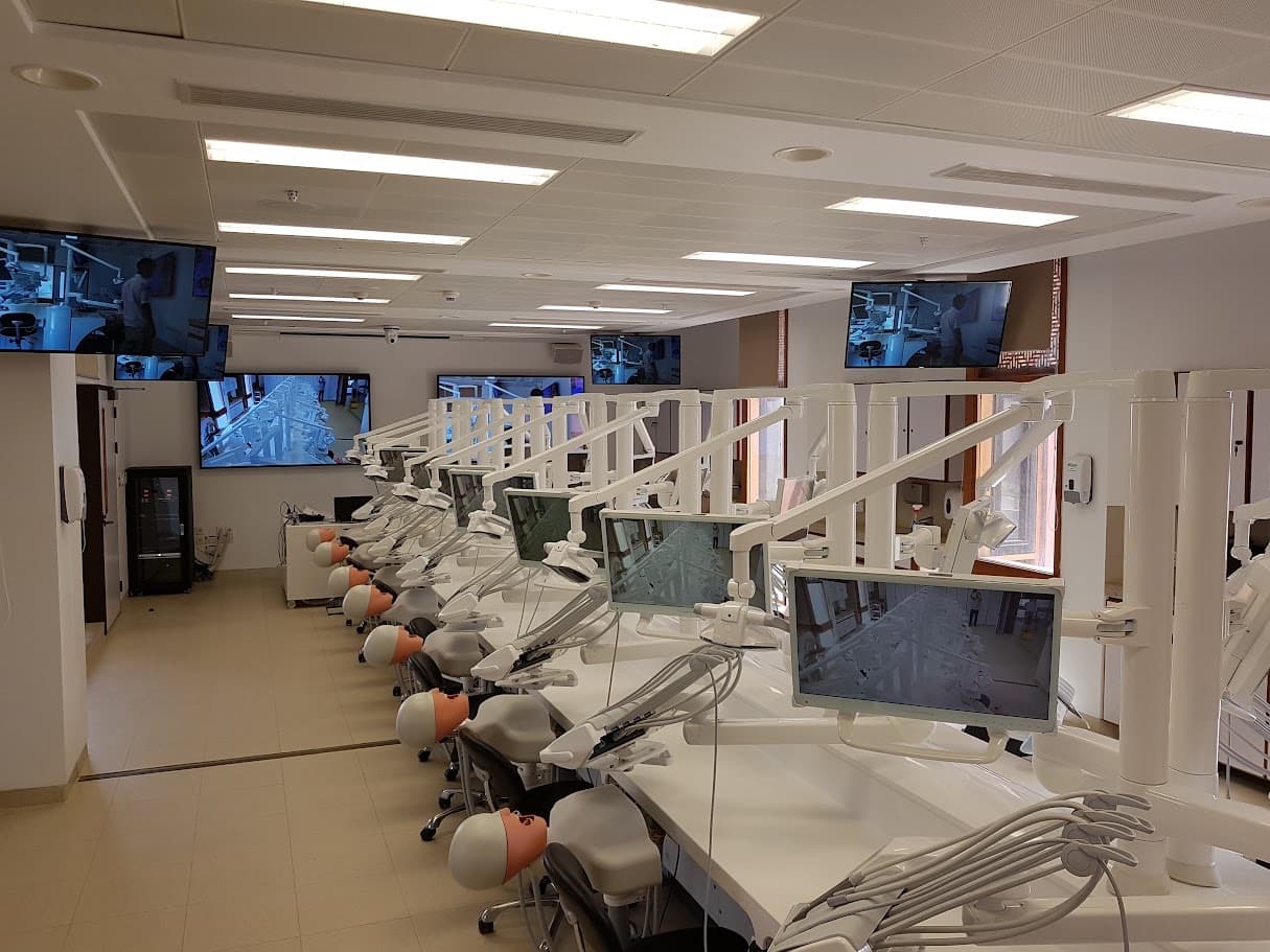 Aga Khan University dental simulation lab with rows of dental training stations and integrated video displays.